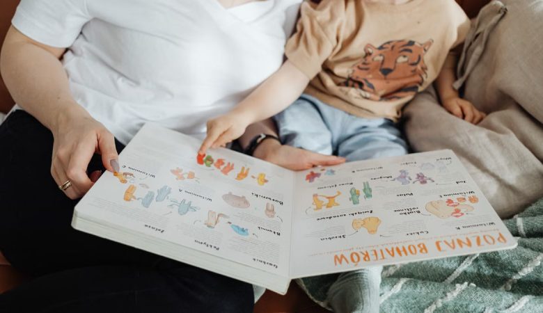 A mother and her son enjoy reading a children's book together while sitting on a cozy couch.